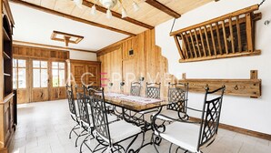 Un espace repas avec une table et des chaises en bois, un lustre et des murs en bois.