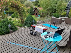 A wooden deck with exercise equipment, a laptop, and a table. - Wonderful 2-bedroom house in Saint-Maurice-sur-Moselle awaits you (Saint-Maurice-sur-Moselle)