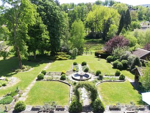 A well-maintained garden with a circular fountain, neatly trimmed hedges, and a variety of trees. - Wonderful 2-bedroom house in Saint-Maurice-sur-Moselle awaits you (Saint-Maurice-sur-Moselle)