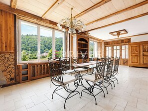 A dining area with a large table and chairs, wooden walls, and a view of greenery through large windows. - Wonderful 2-bedroom house in Saint-Maurice-sur-Moselle awaits you (Saint-Maurice-sur-Moselle)