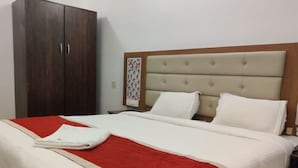 A hotel room with a large bed, a wardrobe, and a nightstand. - Hotel Nesam Grand By M&D Hospitality (Rajapalayam)