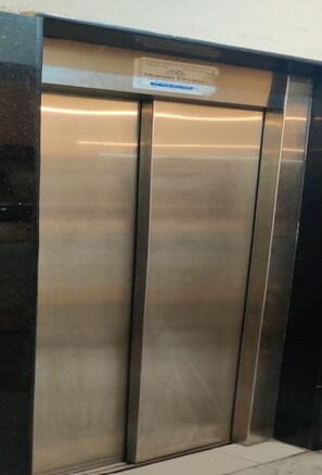 A metallic elevator with a sign above it.