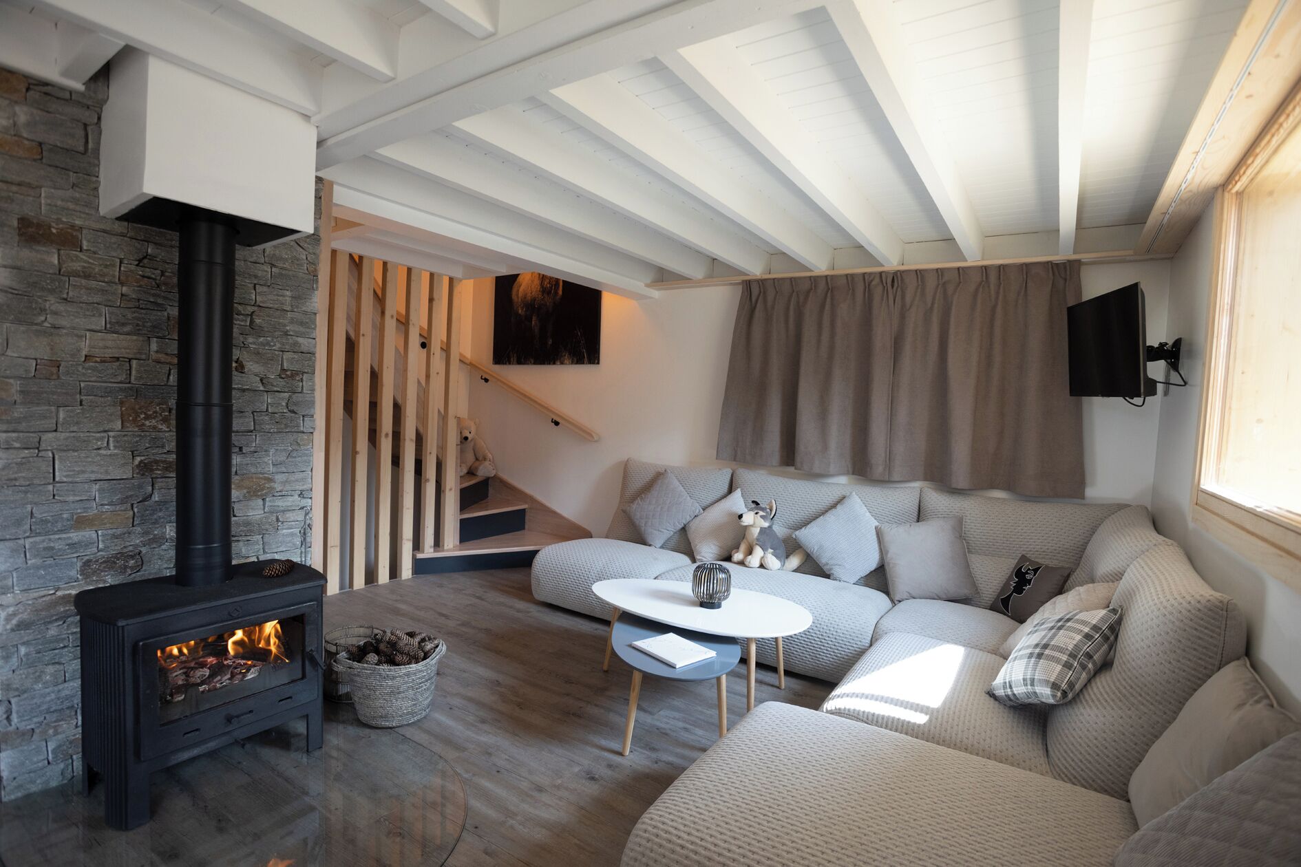 A cozy living room with a fireplace, a sofa set, a coffee table, and a staircase leading to an upper level.