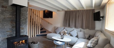 A cozy living room with a fireplace, a sofa set, a coffee table, and a staircase leading to an upper level.