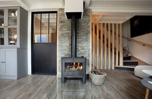 Ein modernes Wohnzimmer mit Kamin, Steinwand und einer Treppe mit Holzgeländern.