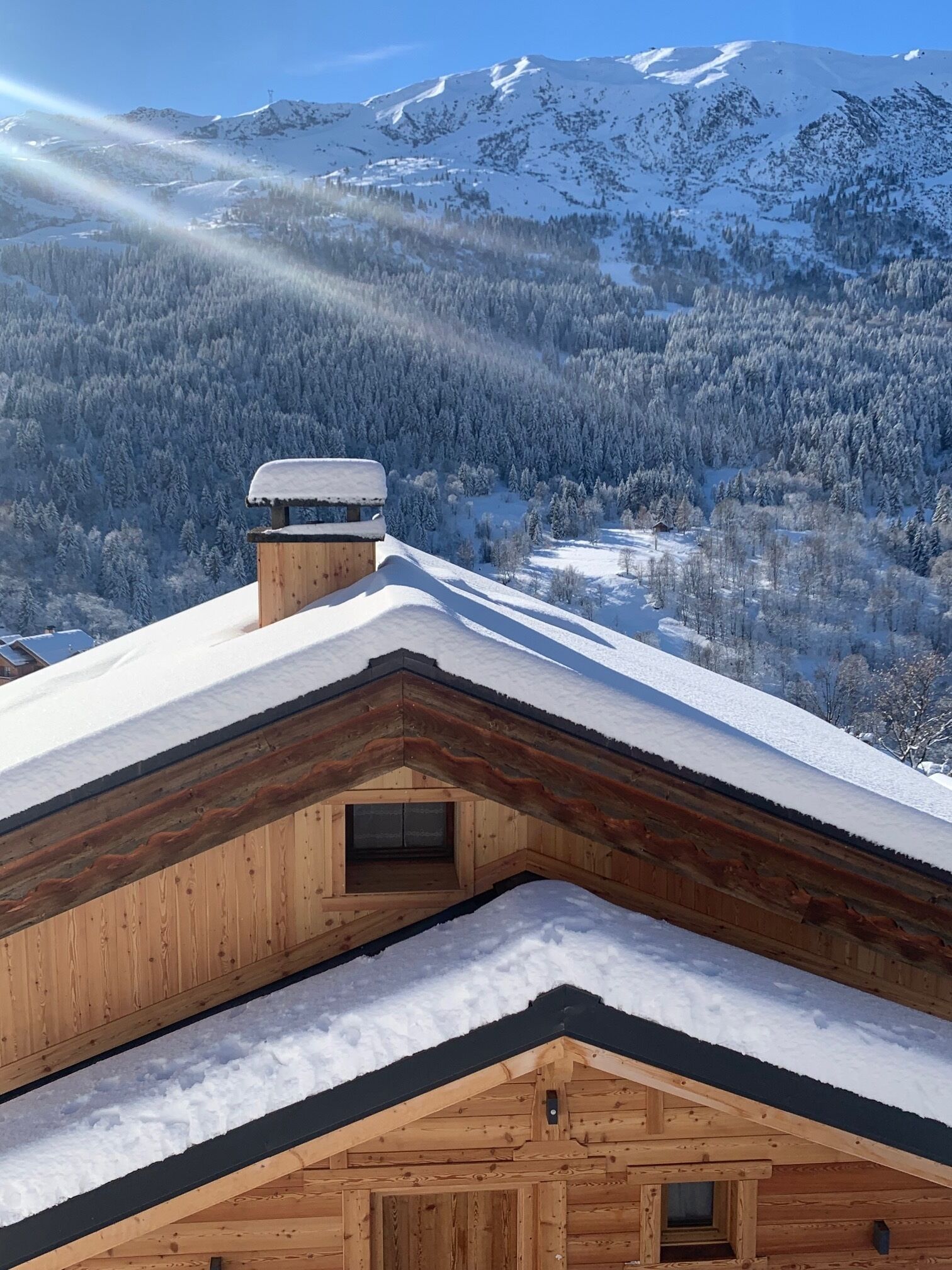 Een houten hutje met een sneeuwbedekt dak en uitzicht op een besneeuwd berglandschap.
