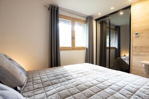 Ein Schlafzimmer mit einem Bett, einem Fenster und einem Holzschrank.