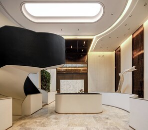 Un interior moderno con una zona de estar circular central, iluminación empotrada y una combinación de paneles de madera y paredes blancas.