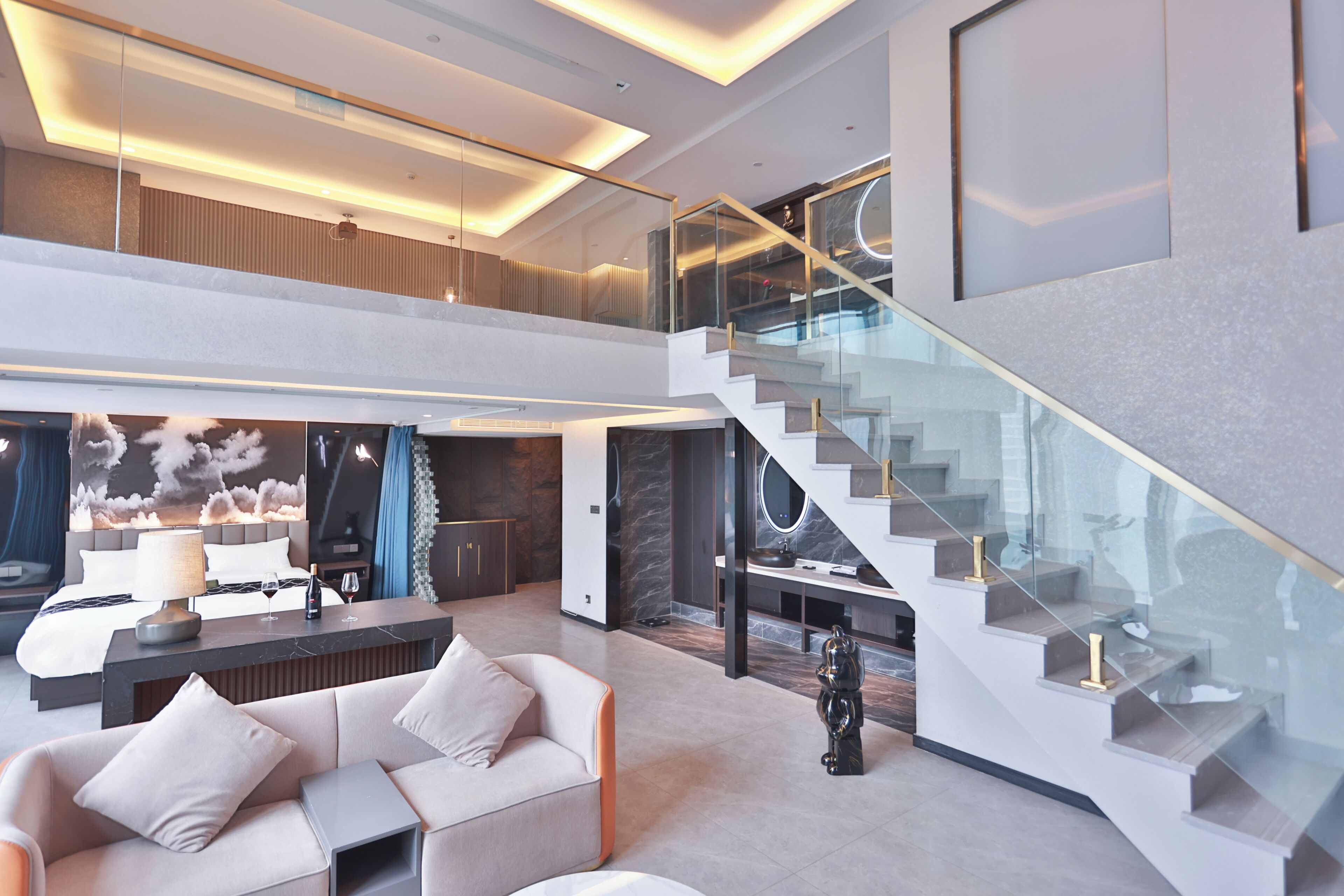 A modern hotel lobby with a high ceiling, a staircase, and a seating area.
