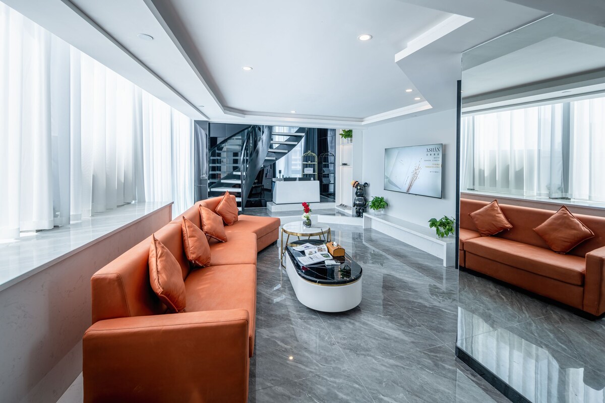 A modern living room with two sofas, a coffee table, and a staircase leading to an upper level.