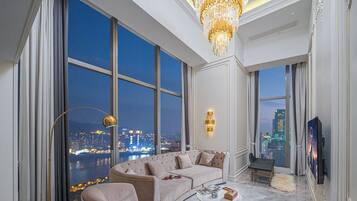 A spacious living room with a large window, a chandelier, and a modern sofa set.