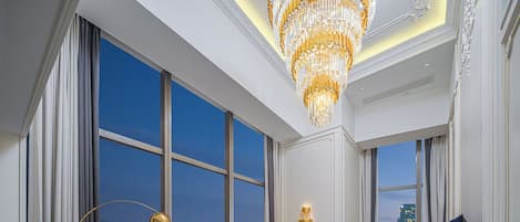 A spacious living room with a large window, a chandelier, and a modern sofa set.