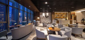 A modern hotel lobby with seating areas, a bar, and a view of the cityscape. - Chongqing Ashan River View Hotel (Yuzhong District)