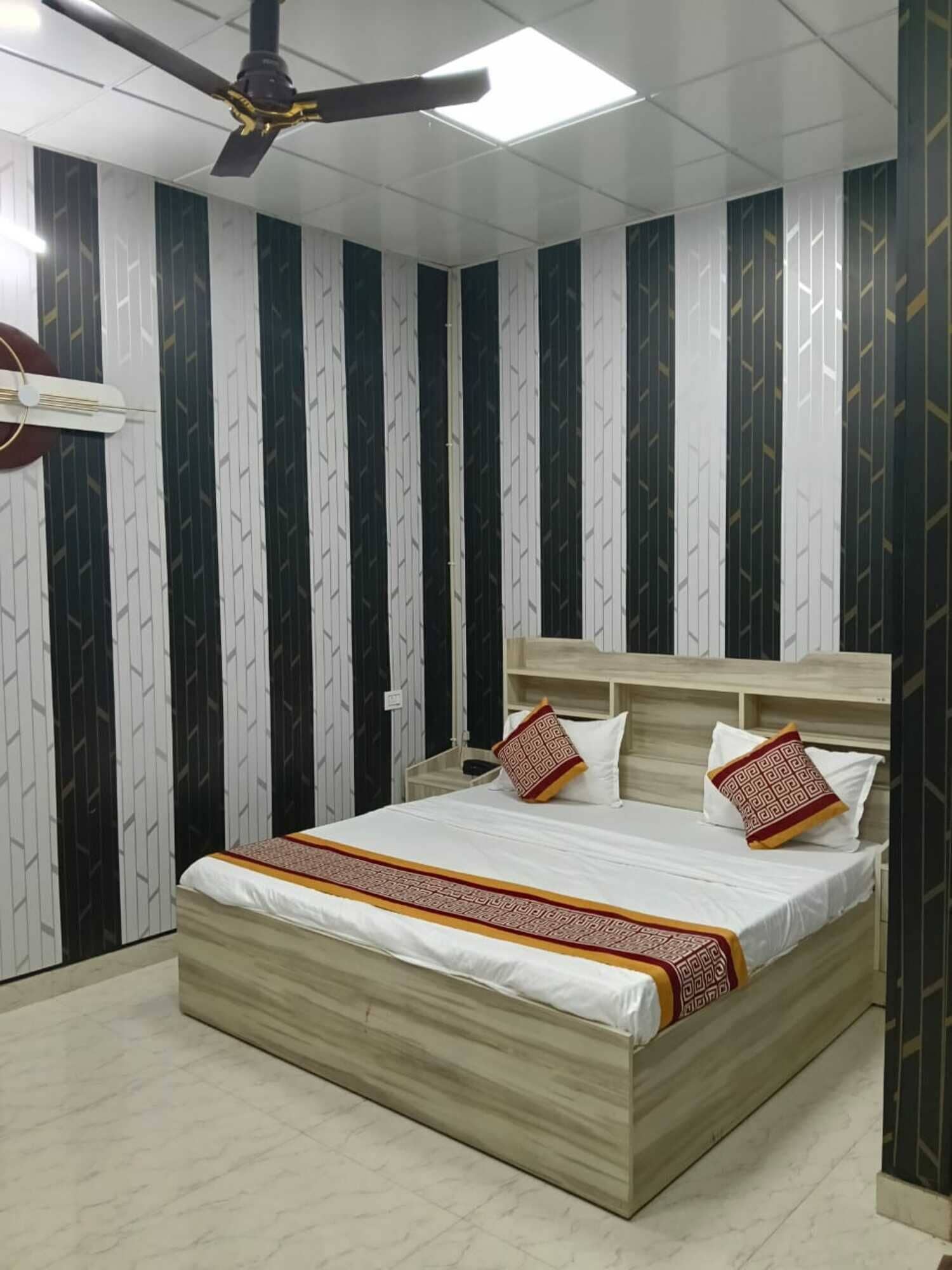 Un dormitorio con cama, ventilador de techo y papel tapiz estampado.