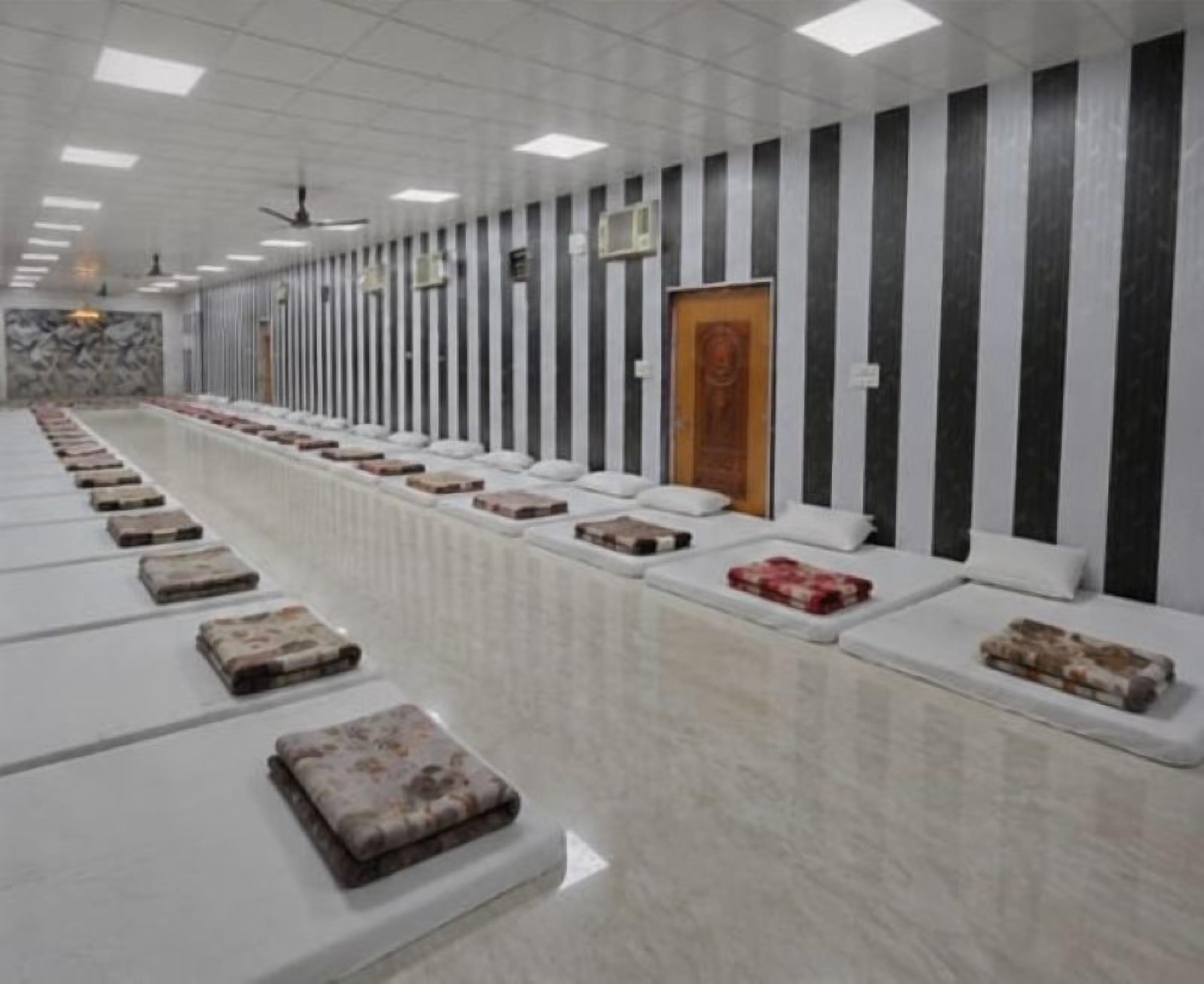 Una habitación amplia con filas de camas y una pared de mármol.