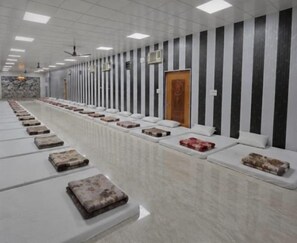Una habitación amplia con filas de camas y una pared de mármol.
