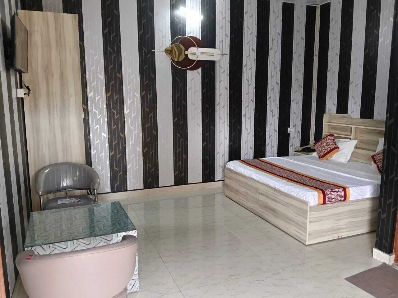 A room with a bed, a table, a chair, and a wall with a striped pattern.