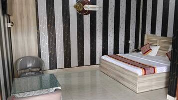 A room with a bed, a table, a chair, and a wall with a striped pattern.