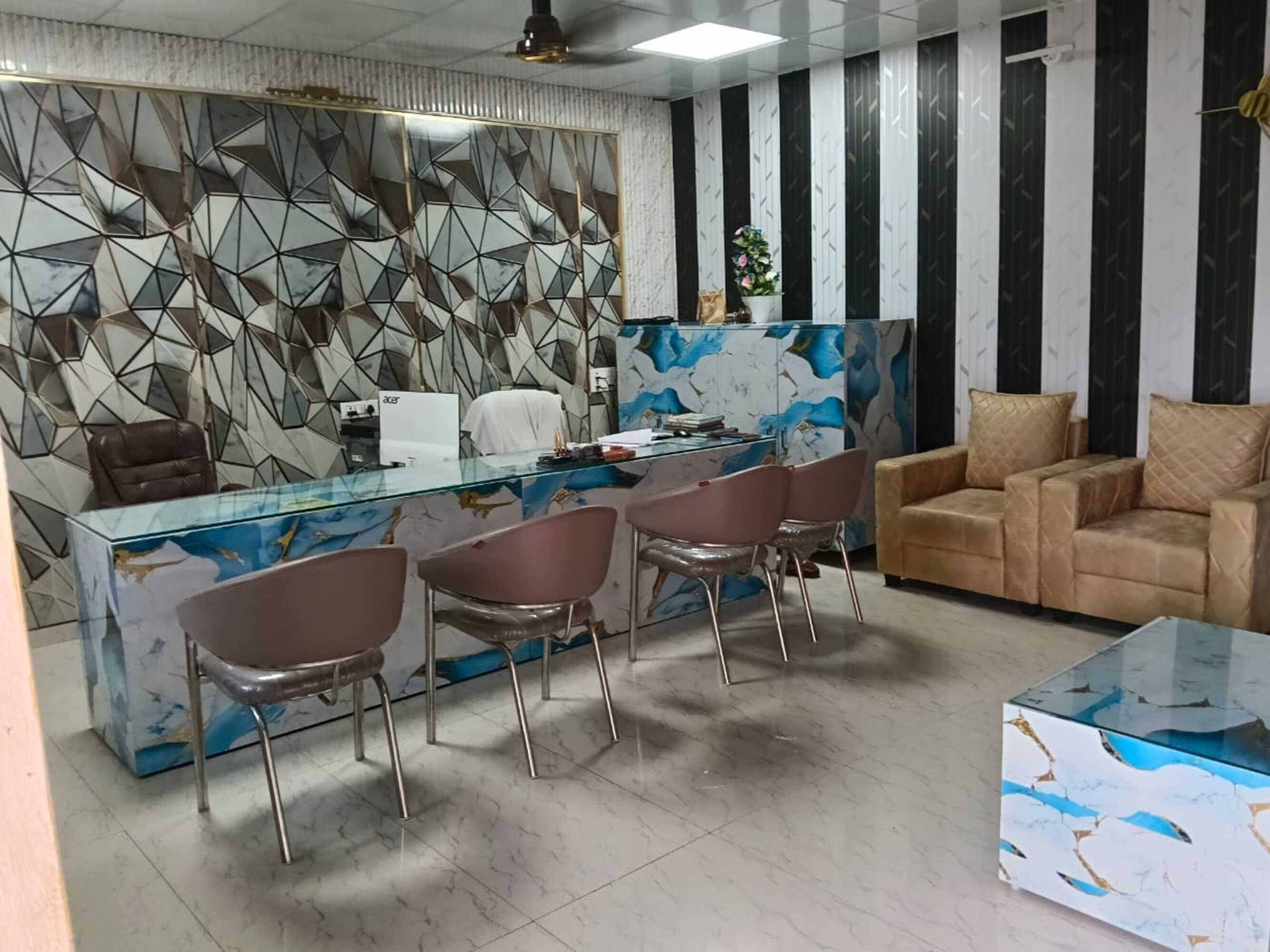 Un espace de bureau moderne avec un bureau en verre, des chaises en métal, un canapé et un mur à motifs.