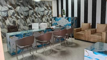 Un espace de bureau moderne avec un bureau en verre, des chaises en métal, un canapé et un mur à motifs.
