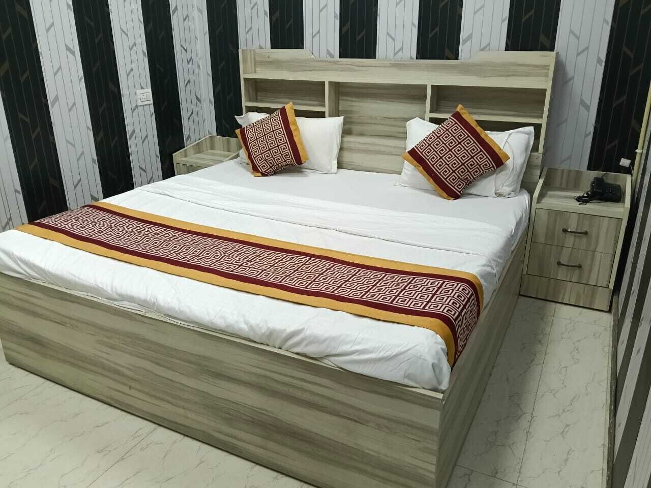 Un lit avec un cadre en bois, une literie blanche et des oreillers à motifs.