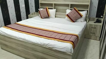 Un lit avec un cadre en bois, une literie blanche et des oreillers à motifs.