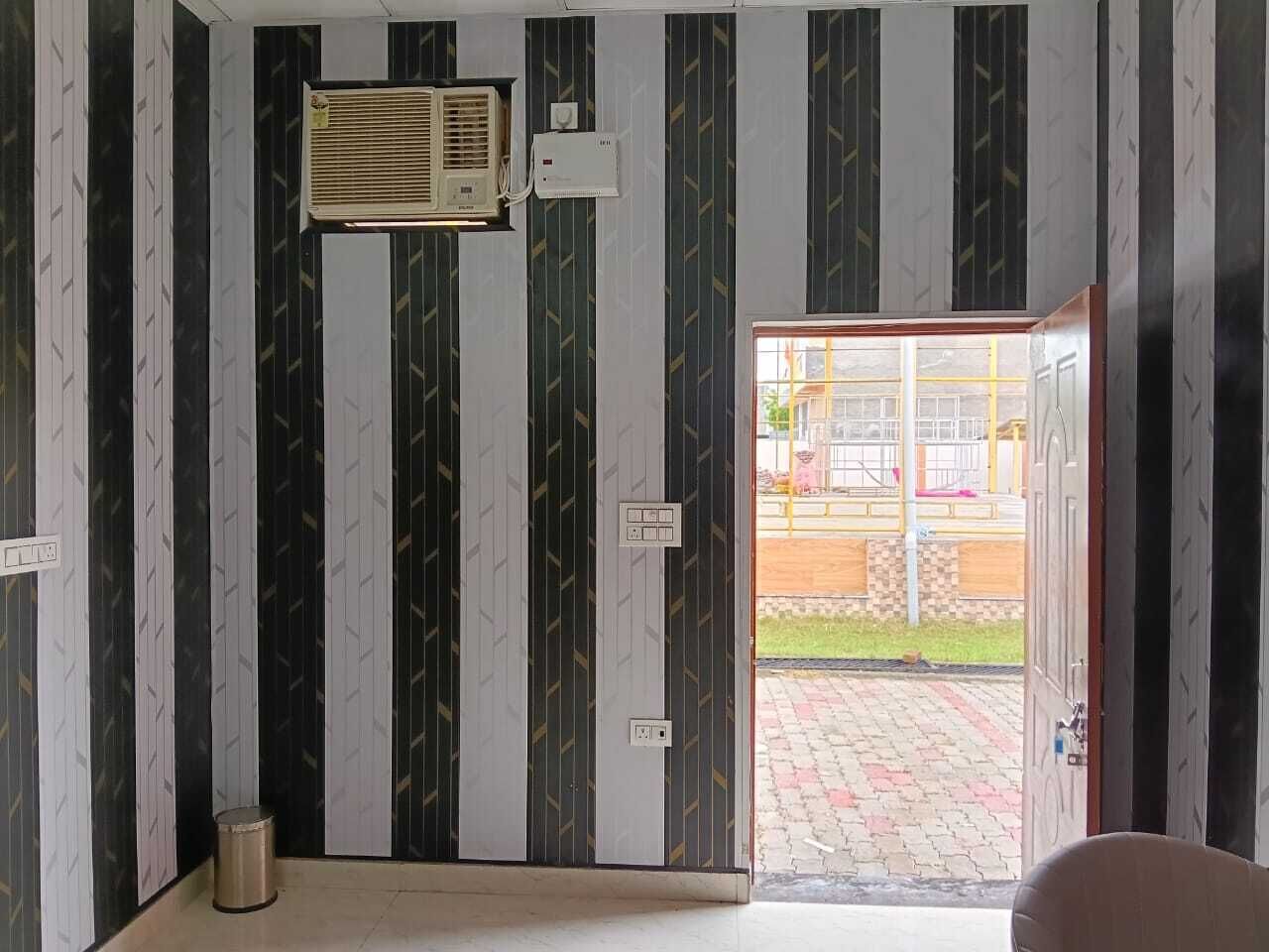 Une pièce avec un papier peint à rayures, une porte donnant sur l’extérieur et une poubelle.