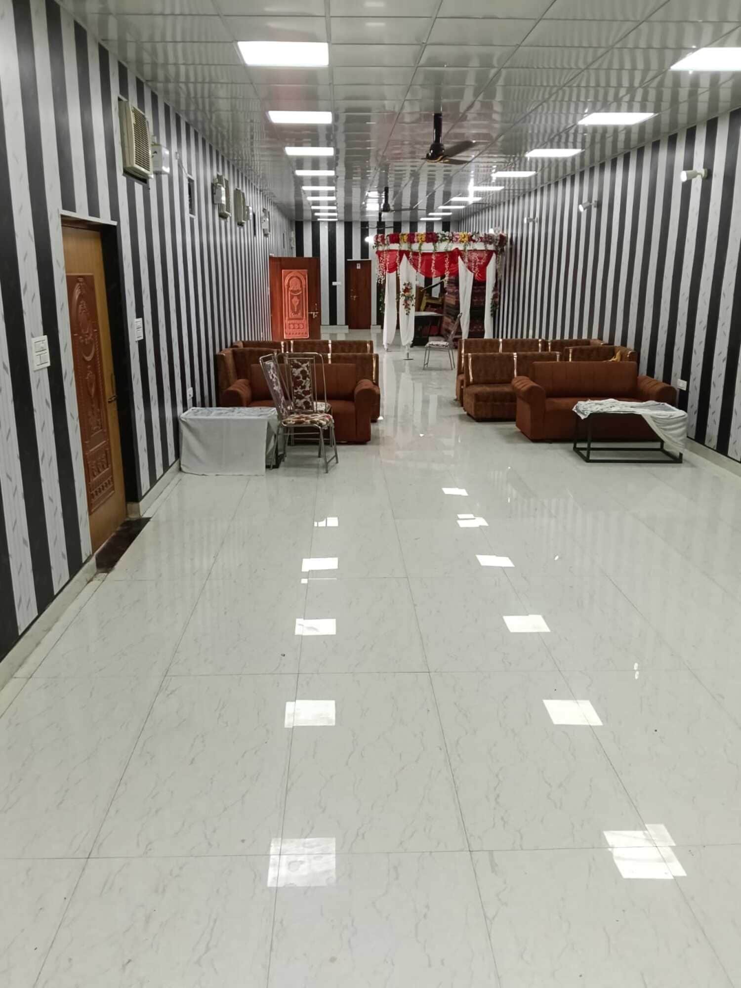 A hallway with striped walls, a reception area with a sofa and chairs, and a door with a decorative panel.