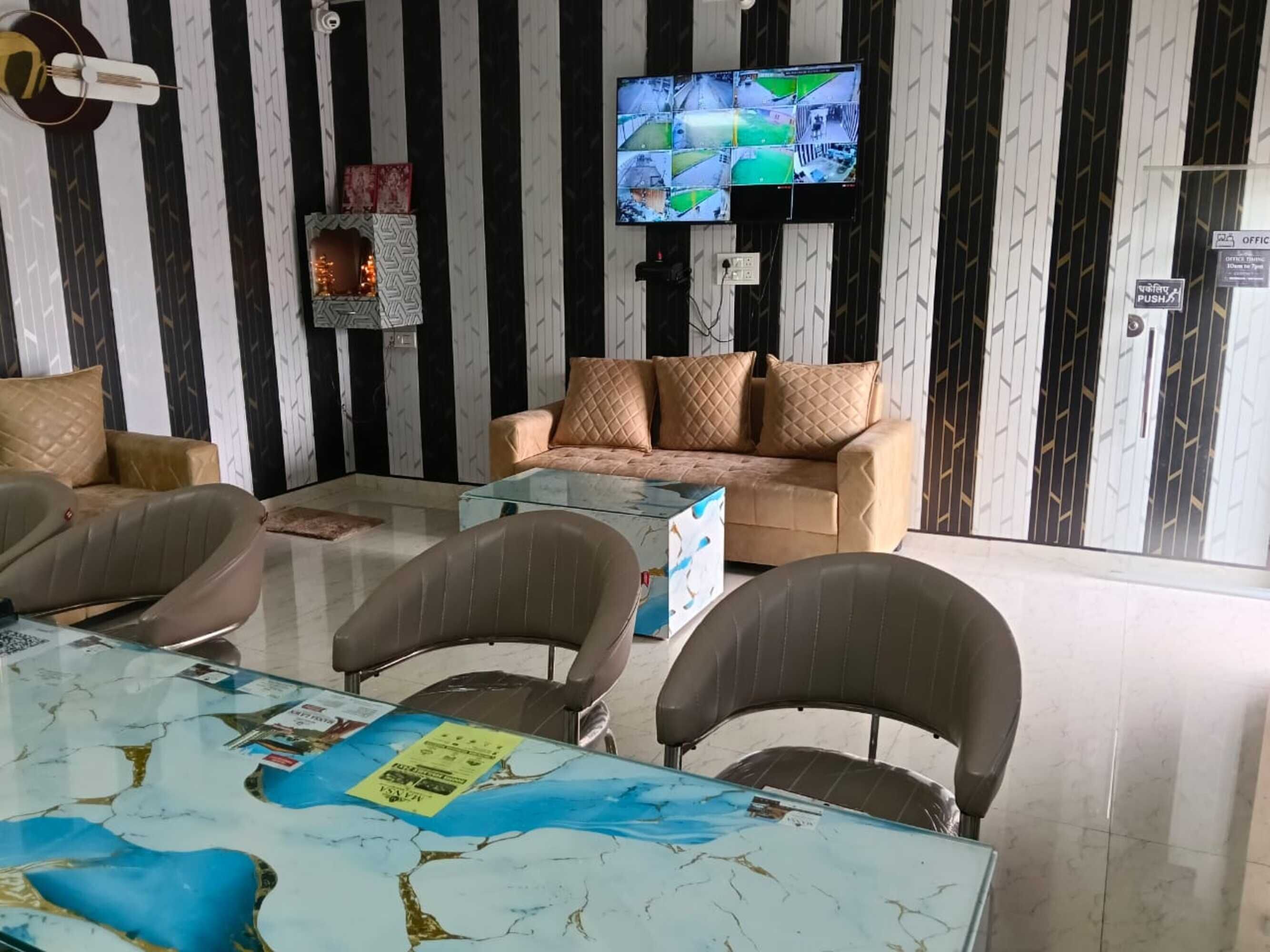 Un soggiorno con divano, poltrone, tavolino da caffè e televisione che mostra diverse riprese video.
