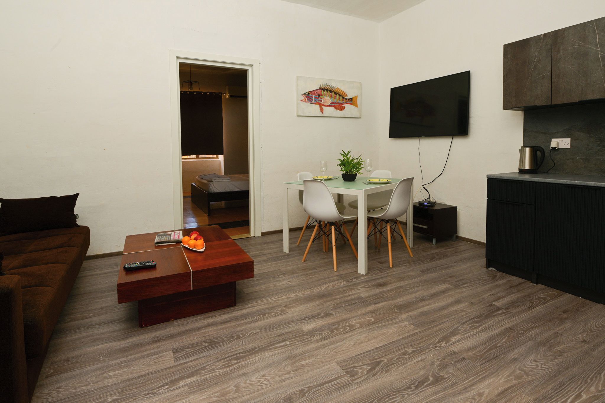 A compact living space with a dining area, a TV mounted on the wall, and a kitchenette.