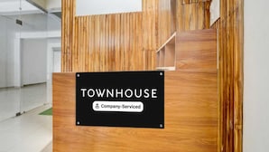 Een receptiebalie met een bord waarop 'TOWNHOUSE' en 'Company-Serviced' staat.