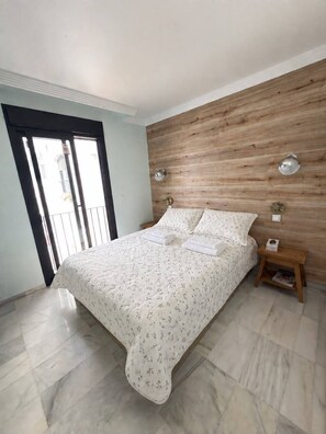 Ein Schlafzimmer mit einem Bett, einem Holzkopfteil, einem Nachttisch und einem Fenster mit Blick.
