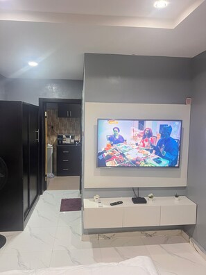 A room with a television mounted on a wall, a white cabinet below it, and a tiled floor.
