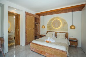 Une chambre avec un grand lit, une tête de lit en bois et un mur en pierre qui sert d’élément décoratif.