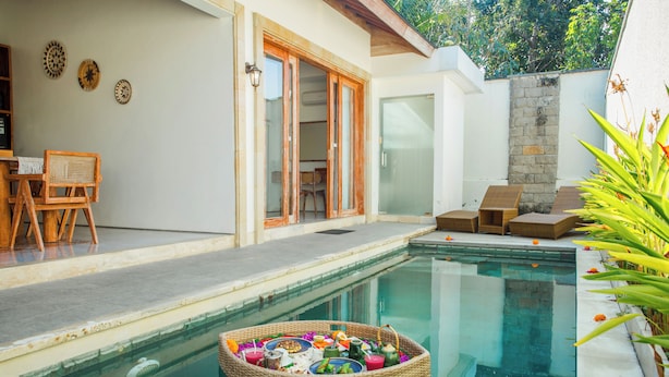 A swimming pool with a floating basket of food and drinks, a glass door entrance, and a seating area with chairs. - Ubud 2BR Villa Private Pool Abhimanyu (Ubud)