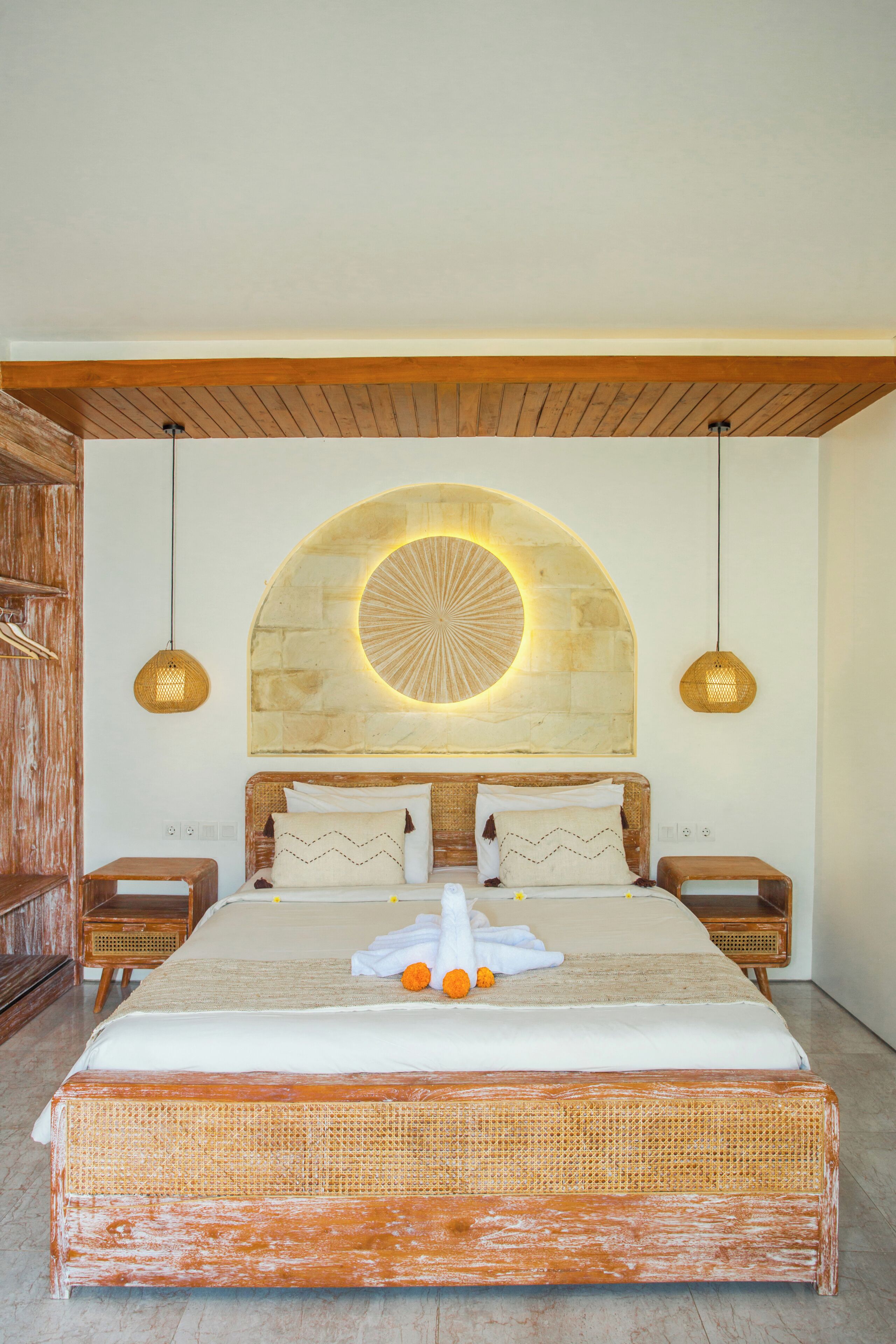 Un dormitorio amplio con una cama grande, cabecera de madera y una lámpara circular original sobre la cama.