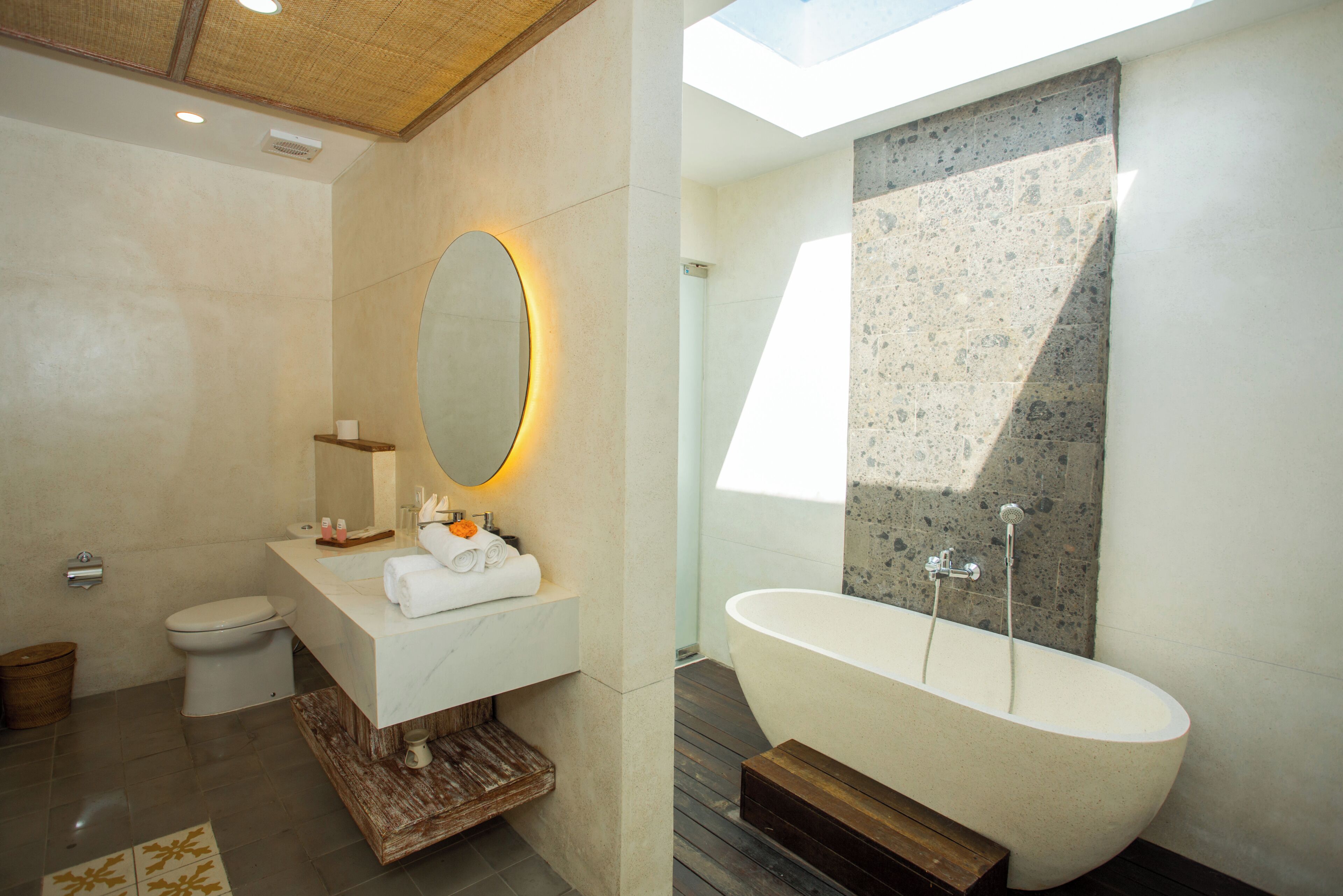 Un baño moderno con una bañera independiente, un espejo grande y un inodoro.