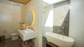 Un baño moderno con una bañera independiente, un espejo grande y un inodoro.