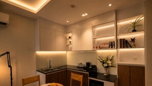 A modern kitchen with a dining area, featuring a built-in oven, a sink, and a refrigerator. - One Studio Suite by PSH (Ou Chrov)