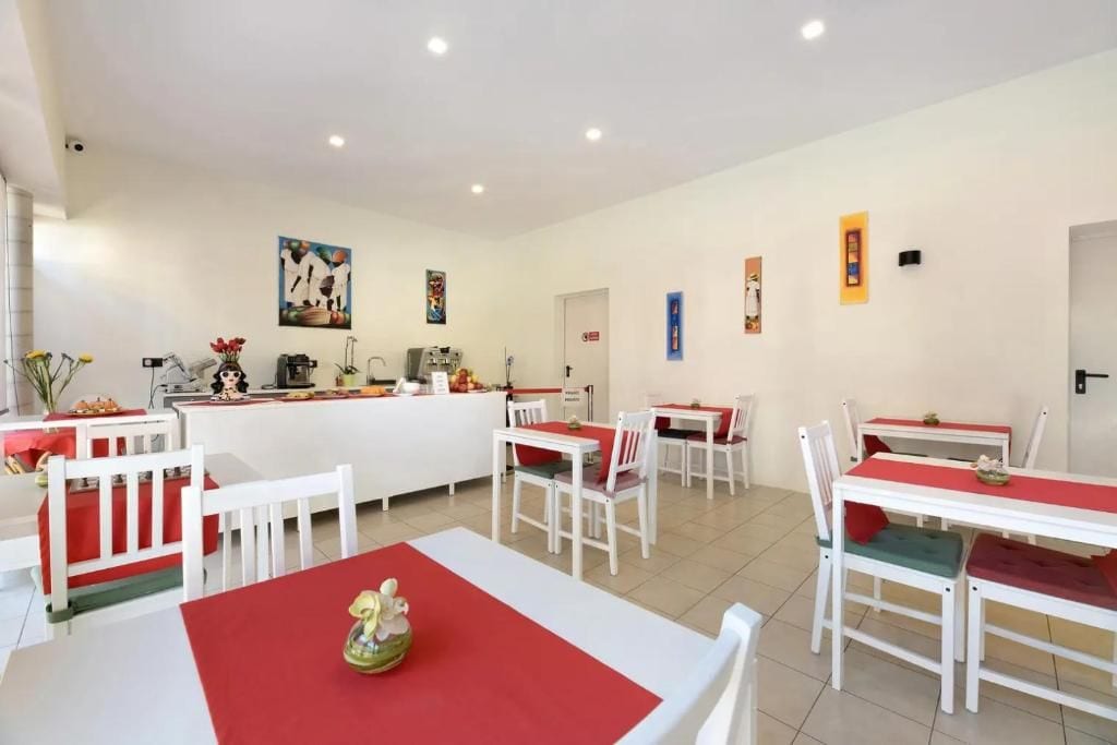 A dining area with white tables and chairs, a central counter, and artwork on the walls.
