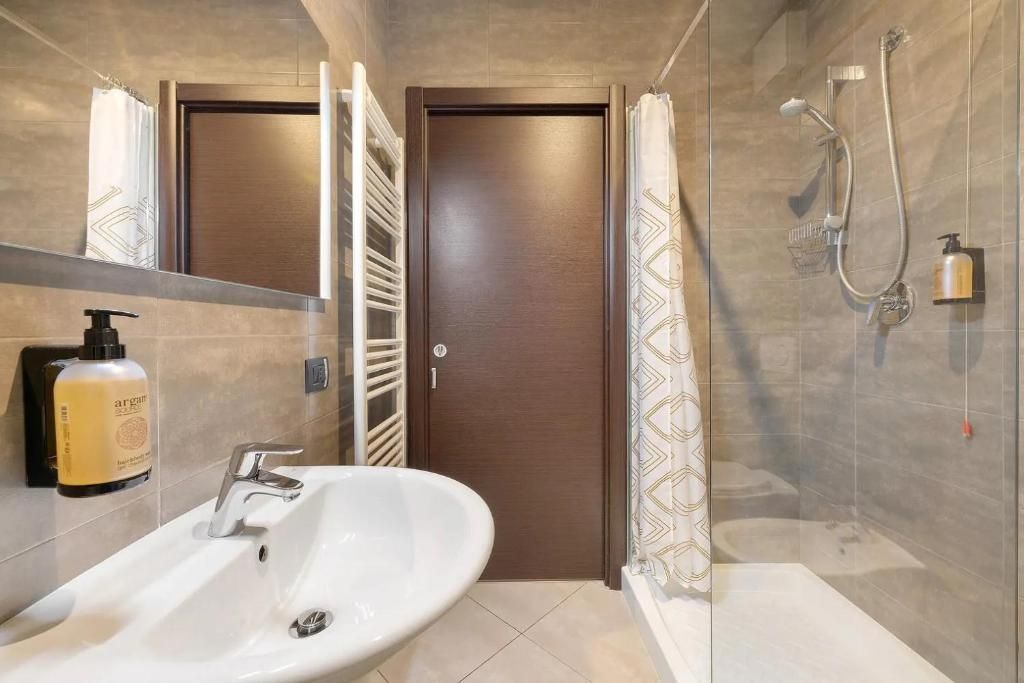 A modern bathroom with a white sink, a shower with a handheld showerhead, and a towel rack.