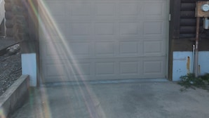 A garage door with a utility meter and a small window to the right.
