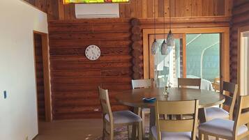 Ein Holzkamin mit Esstisch, Stühlen, einer Uhr und einem Buntglasfenster.