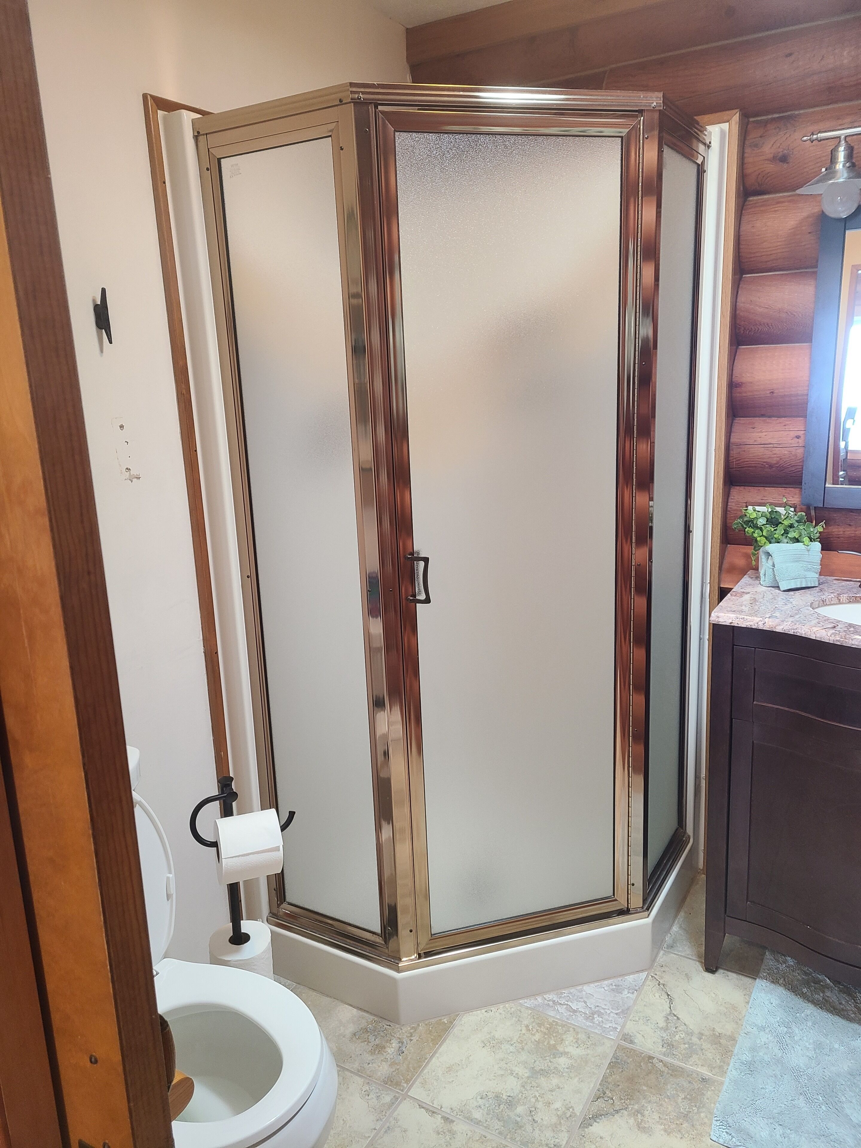 Ein Badezimmer mit Eckdusche, Toilette und Waschbecken mit Spiegel darüber.