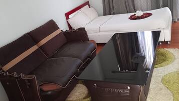 Uma sala de estar com um sofá de couro marrom, um sofá branco, uma mesa de centro e um tapete estampado.