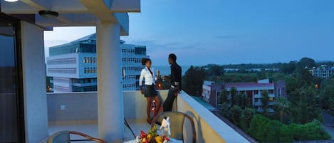 A balcony with a table set for two, overlooking a cityscape.