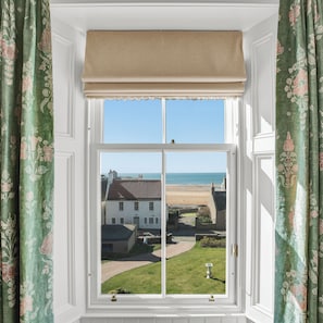 A window with a view of a beach and buildings. - Russell Bank is a beautiful house with amazing sea views in the heart of Elie. (Elie and Earlsferry)