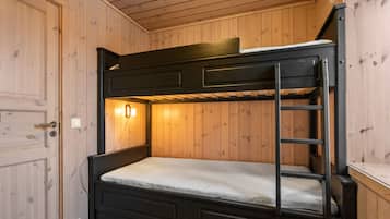 Una cama litera con escalera, una luz fijada en la pared y una puerta de madera.
