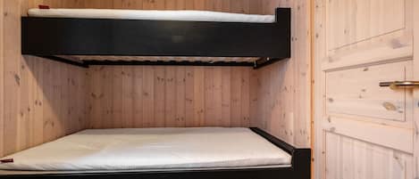 A bunk bed with a mattress and a door to the right.