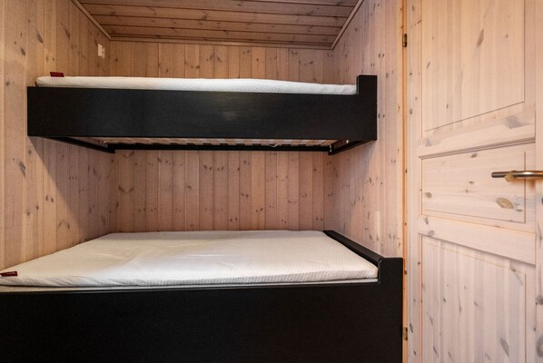 Un llit superposat amb un matalàs i una porta a la dreta.